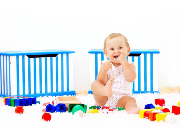 Bebé sonriendo sentado al lado de sus juguetes
