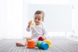 Bebé de 8 meses sentado agarrando sus juguetes